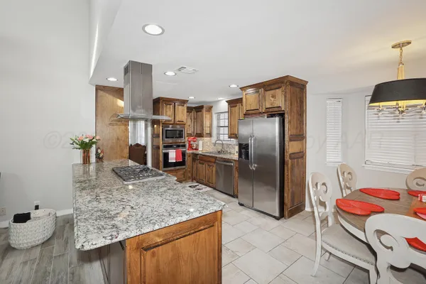 a kitchen with stainless steel appliances granite countertop a refrigerator oven a sink and chairs