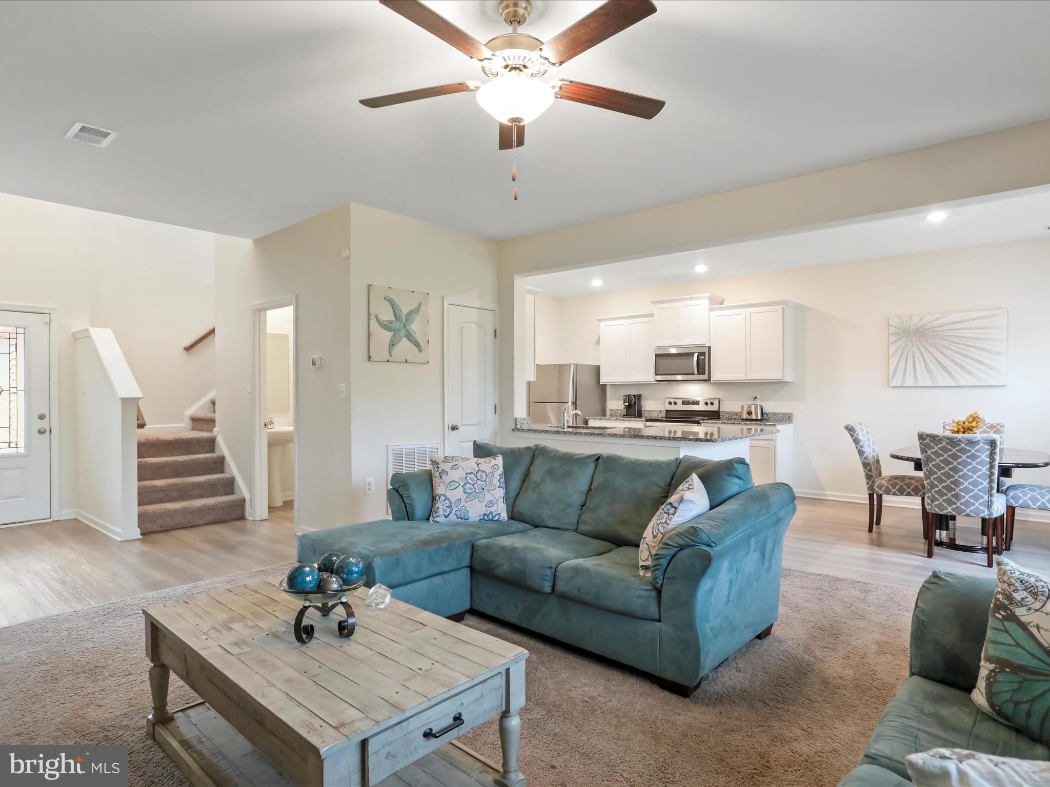 a living room with furniture kitchen view and a chandelier