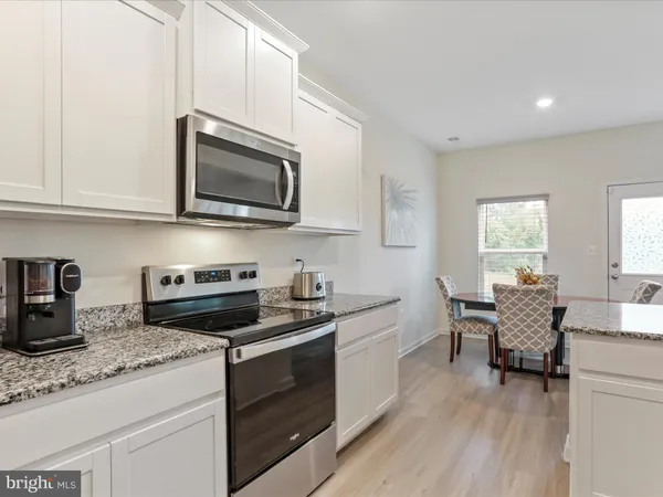 a kitchen with granite countertop a sink cabinets stainless steel appliances and a window