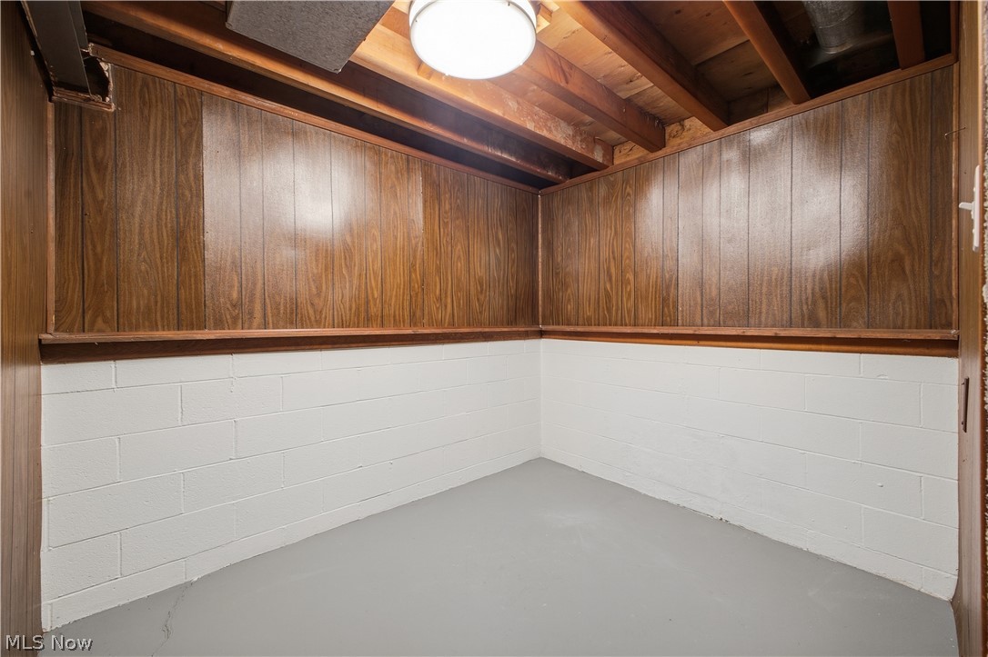 4845 New Road Austintown, OH 44515 - Photo 23 of 40 Exposed ceiling joists, wood paneling, white painted concrete block walls, painted concrete floor, and overhead lighting