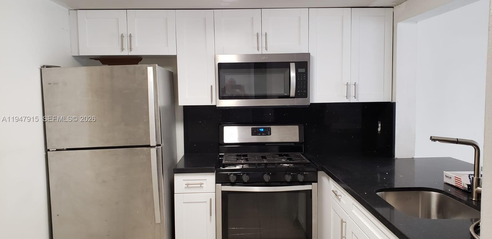 17901 Northwest 68th Avenue, Unit Q201 Hialeah, FL 33015 - Photo 2 of 6 a kitchen with a refrigerator and a sink