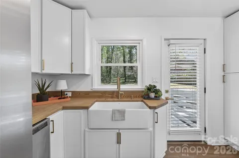 a view of a kitchen that shows a sink and dishwasher with wooden floor