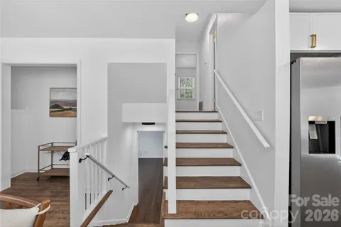 a view of staircase with lots of frames on wall and a dining table