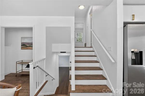 a view of staircase with lots of frames on wall and a dining table