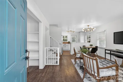 a view of a livingroom with furniture wooden floor windows and a chandelier