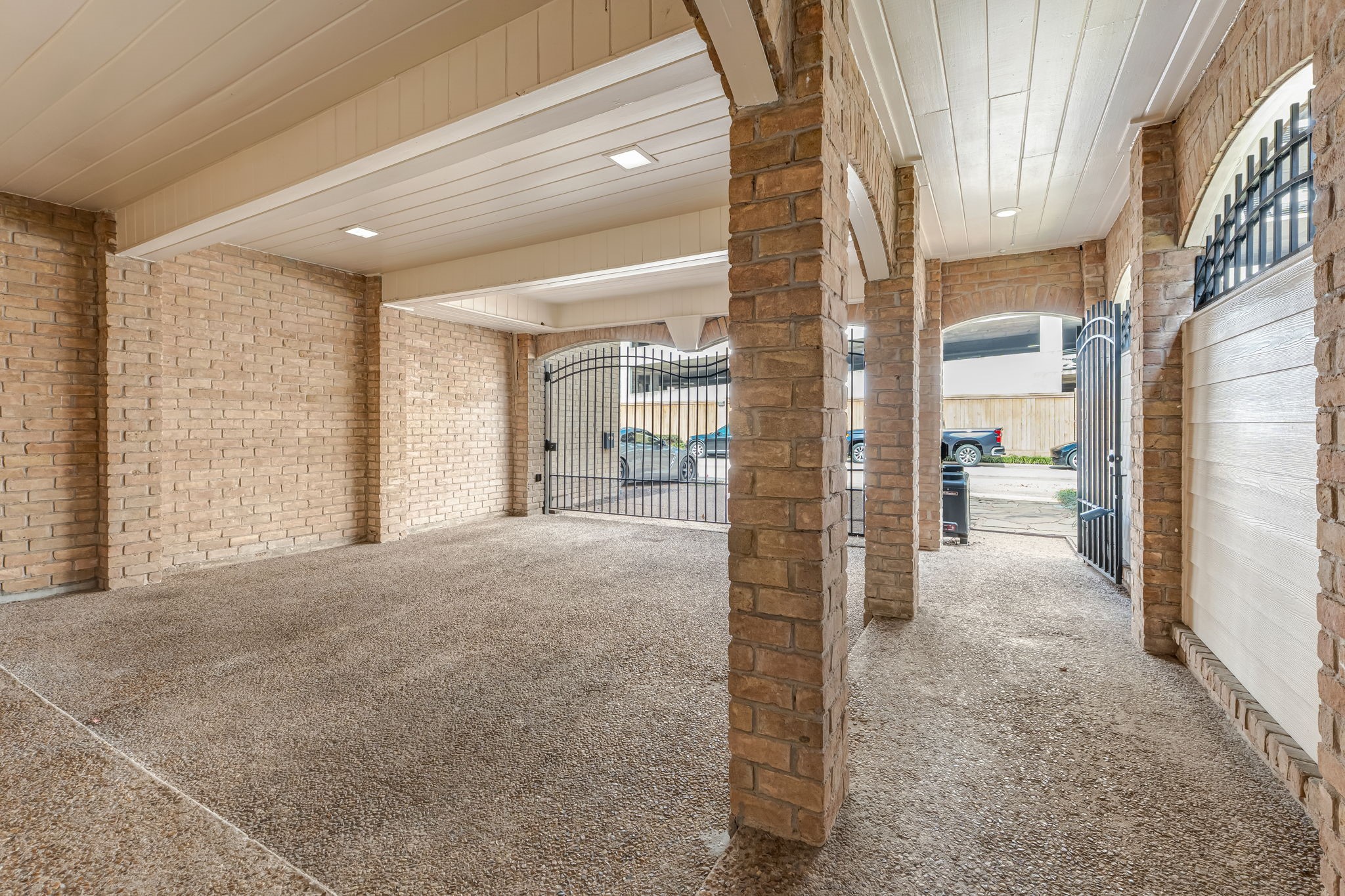 516 South Post Oak Lane, Unit 18 Houston, TX 77056 - Photo 2 of 20 Covered parking area with overhead lighting, secured by a gated entry. Spacious two-car garage with additional driveway access provides convenience and privacy within the controlled-access community.