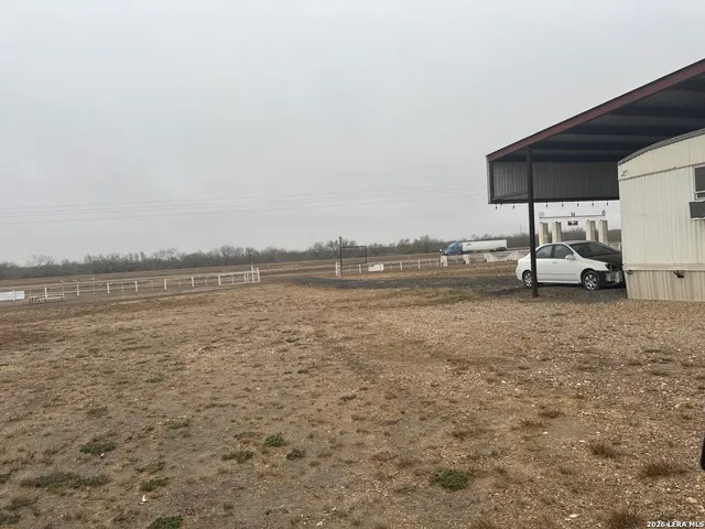 a view of a lake with lawn chairs and large trees