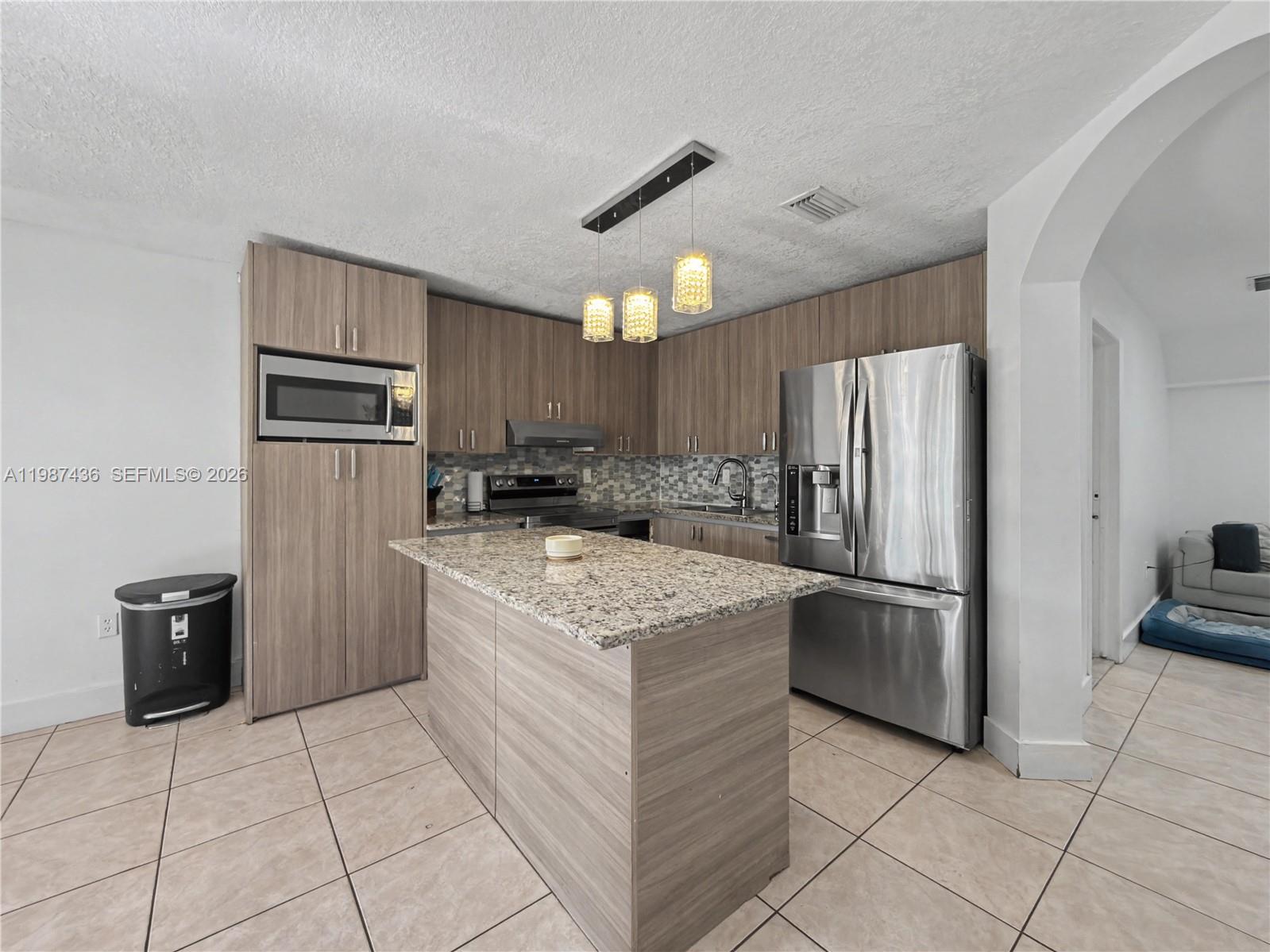 a kitchen with stainless steel appliances granite countertop a refrigerator oven a stove top oven and a refrigerator