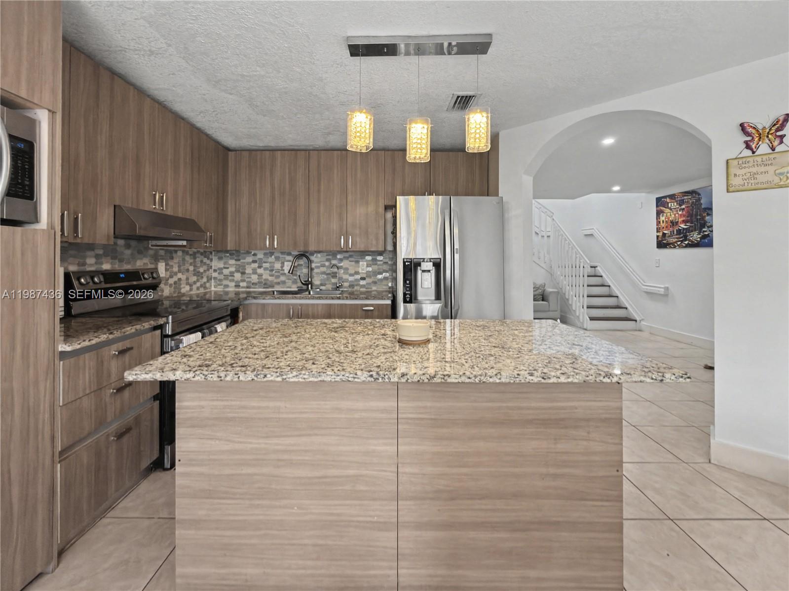 16004 Southwest 87th Terrace Miami, FL 33193 - Photo 2 of 30 a kitchen with kitchen island granite countertop a sink and cabinets