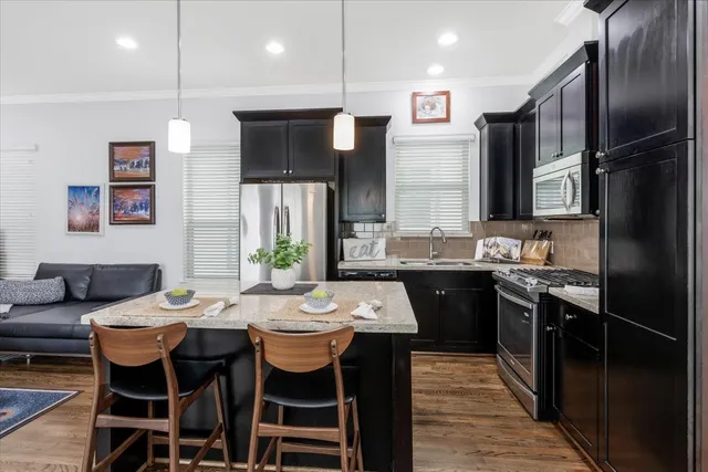 a kitchen with stainless steel appliances granite countertop a sink a stove a refrigerator a dining table and chairs