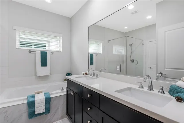 a bathroom with a double vanity sink a mirror and a bathtub
