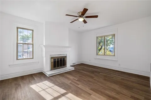an empty room with wooden floor ceiling fan and windows