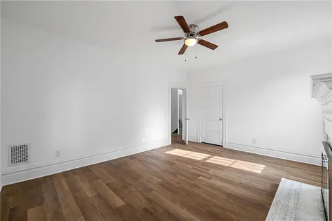 an empty room with wooden floor windows and fan