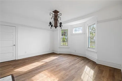 a view of a livingroom with wooden floor a ceiling fan and windows