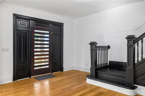 a view of empty room with wooden floor and fan