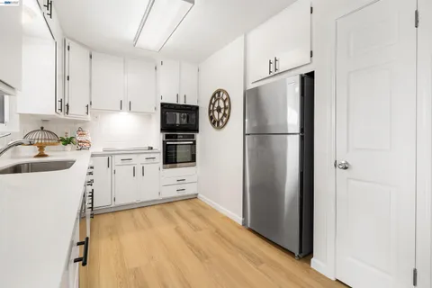 a kitchen with a refrigerator sink stove and wooden floor