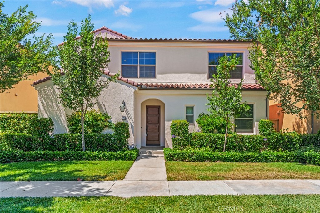 a front view of a house with a garden and trees