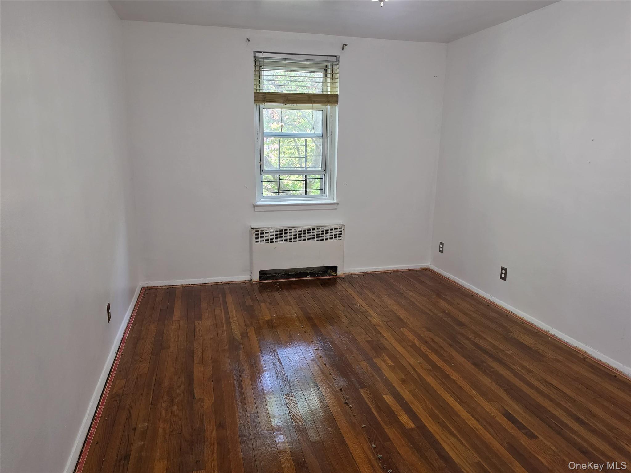 765 Bronx River Road, Unit 3F Bronxville, NY 10708 - Photo 19 of 28 Room featuring wood-finish flooring, a double-hung window with blinds, and a baseboard heating unit