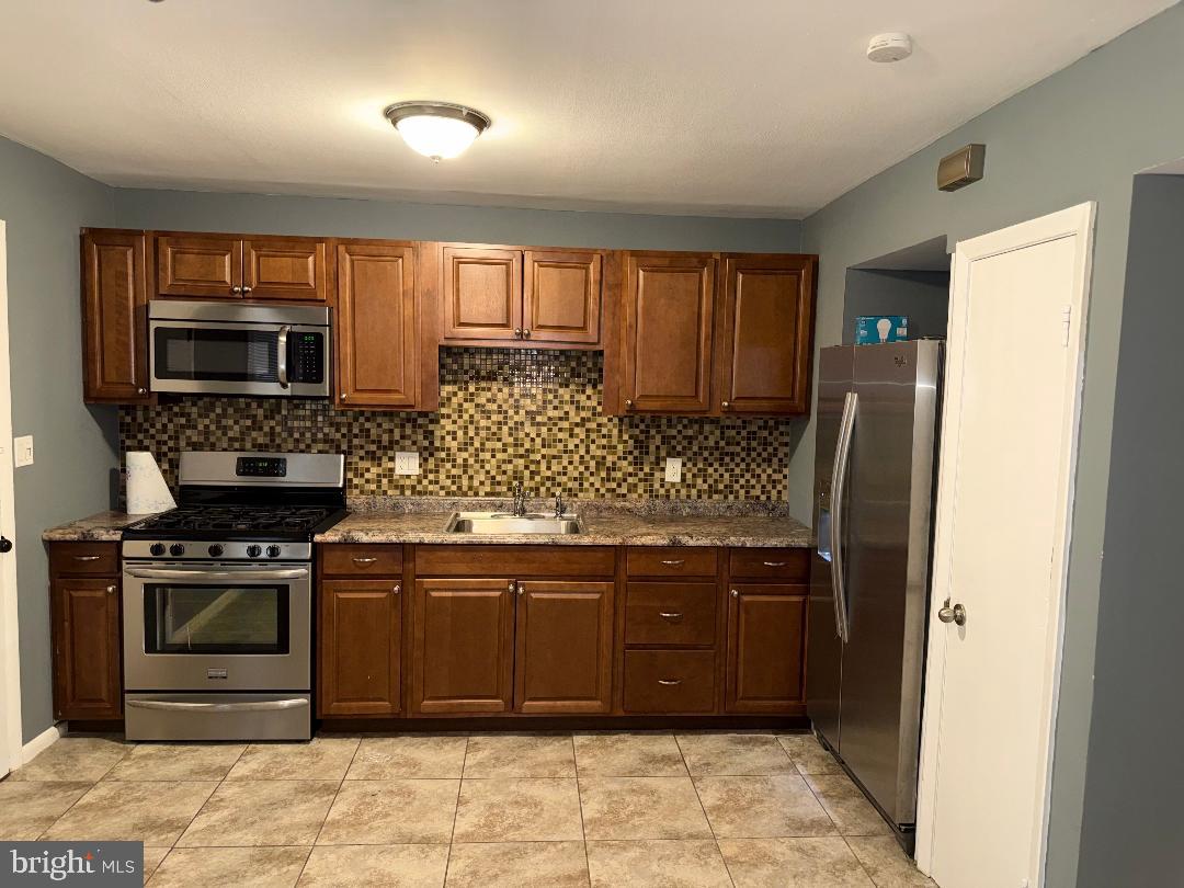 645 Queensgate Road Baltimore, MD 21229 - Photo 3 of 21 a kitchen with stainless steel appliances granite countertop a stove a sink and a refrigerator