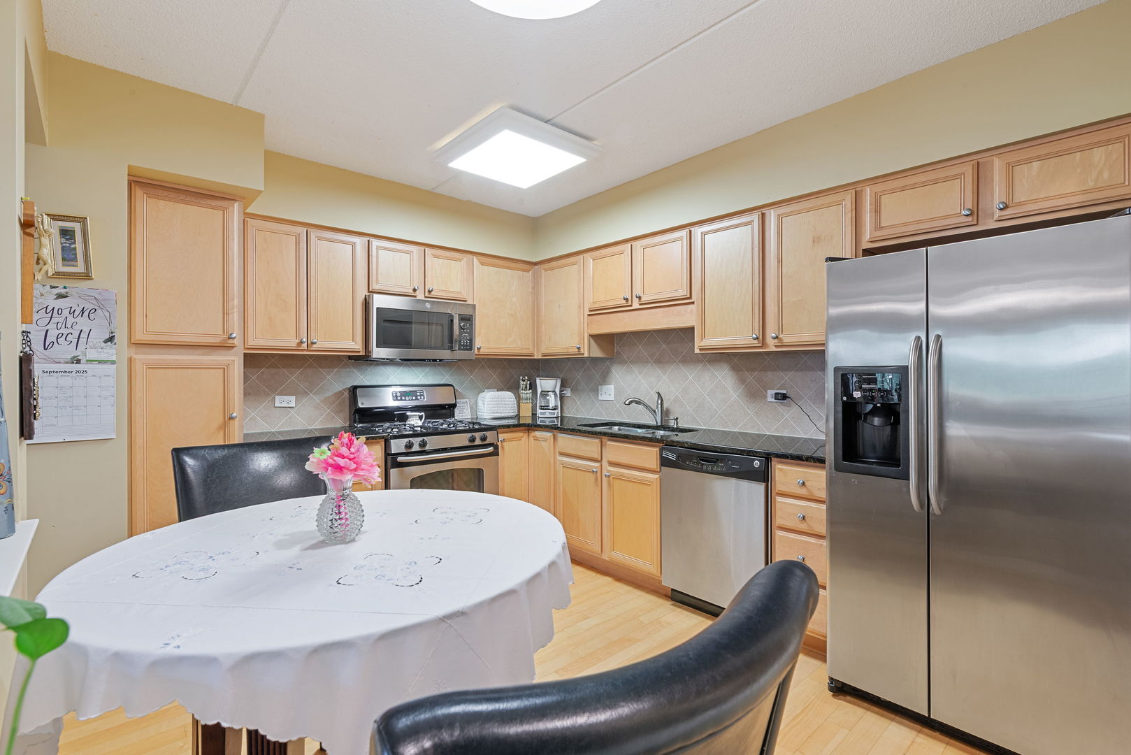 225 Main Street, Unit 201 Roselle, IL 60172 - Photo 6 of 21 a kitchen with stainless steel appliances granite countertop a refrigerator a sink a stove a dining table and chairs