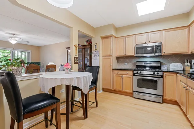 a kitchen with stainless steel appliances a stove a sink cabinets and a dining table