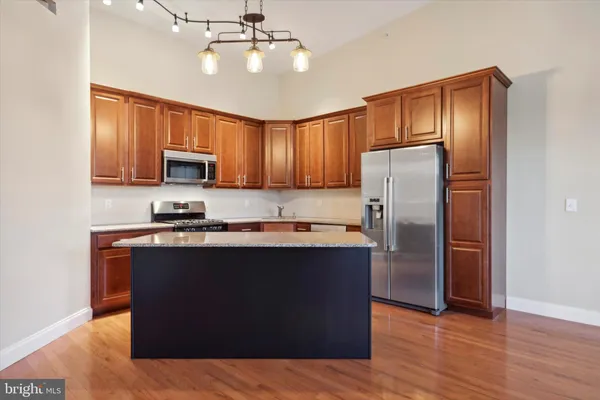 a kitchen with stainless steel appliances granite countertop a refrigerator a stove top oven a sink and dishwasher with wooden floor