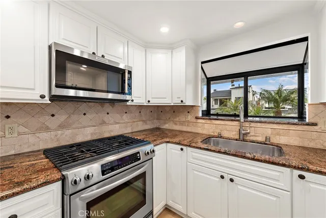 a kitchen with granite countertop a stove sink and microwave