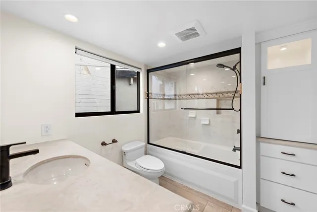 a bathroom with a granite countertop sink mirror vanity and toilet