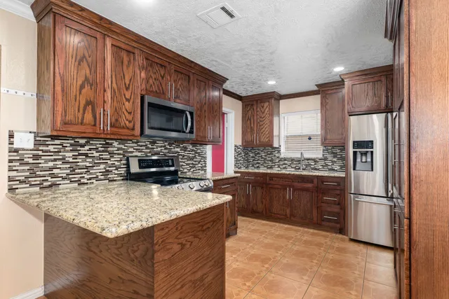 a kitchen with stainless steel appliances granite countertop a refrigerator a stove top oven a sink and dishwasher