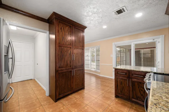 a view of kitchen with stainless steel appliances granite countertop a refrigerator and wooden cabinets