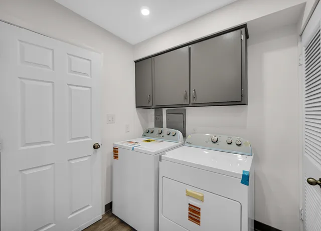 a view of a white house with a large tree and wooden fence