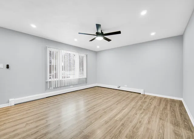 a view of an empty room with a window and wooden floor