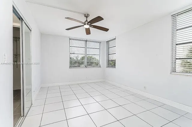 an empty room with windows and fan