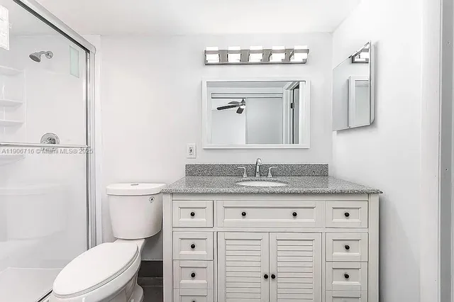 a bathroom with a granite countertop toilet sink and mirror