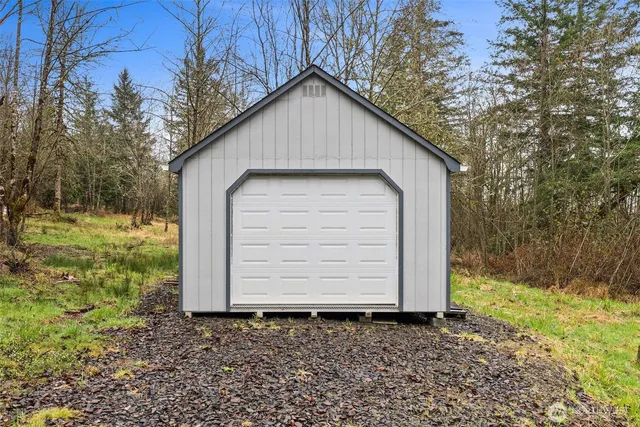 a small white house with a small yard and large trees