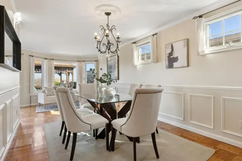 a view of a dining room with furniture a chandelier and wooden floor