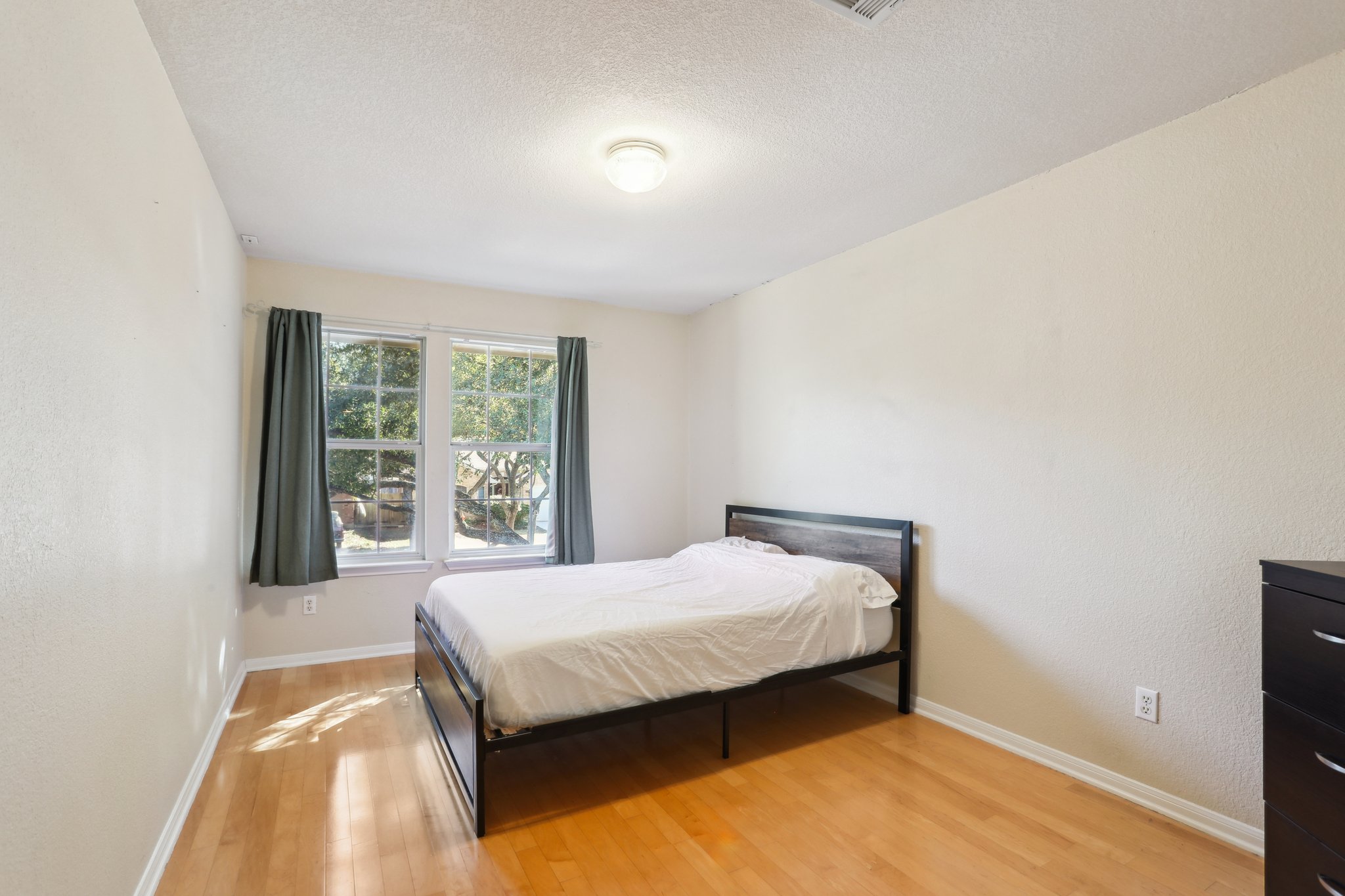 13541 Anarosa Loop Austin, TX 78727 - Photo 21 of 27 Room featuring wood-finish flooring, two large windows, white walls, and a ceiling-mounted light fixture