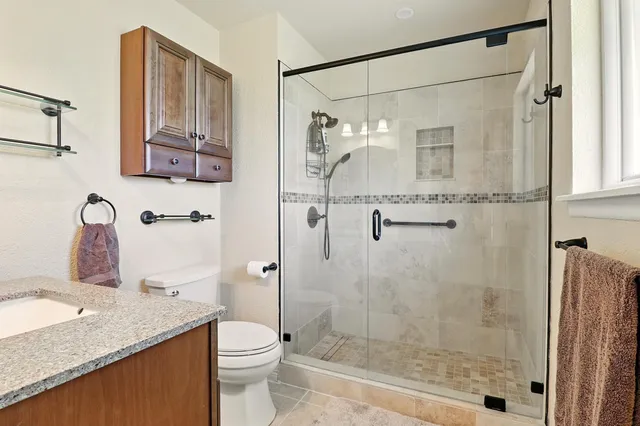 a bathroom with a granite countertop sink a toilet and shower