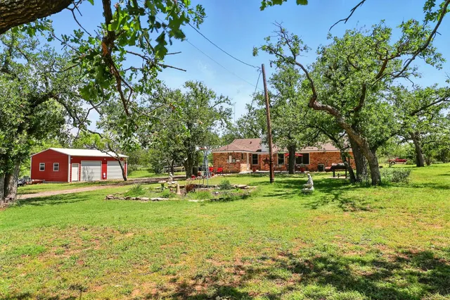 a view of a big yard in front of a house with a large tree