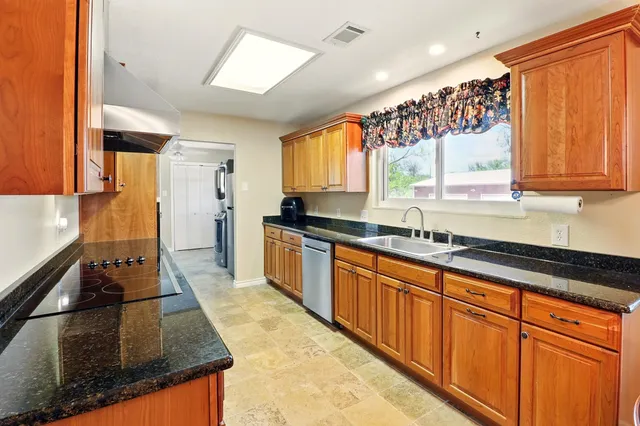 a kitchen with stainless steel appliances granite countertop a sink stove and cabinets