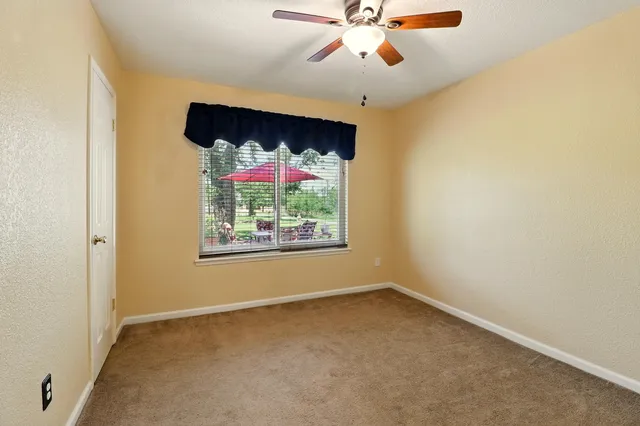 an empty room with a window and a fan