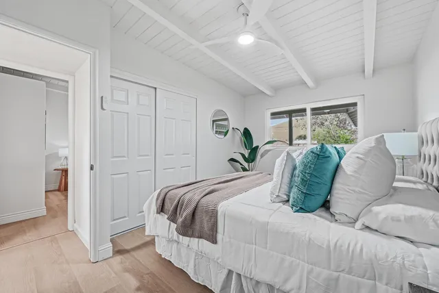 a bedroom with a large bed and a chandelier fan