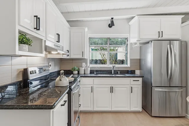 a kitchen with stainless steel appliances granite countertop a sink a stove and a refrigerator