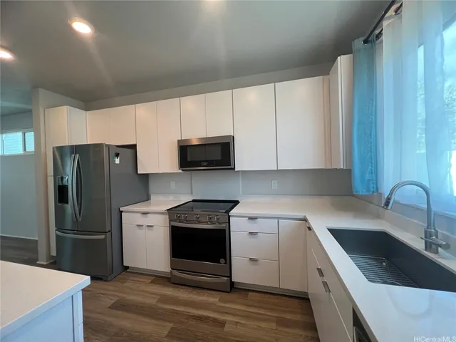 a kitchen with granite countertop a sink a counter space appliances and cabinets