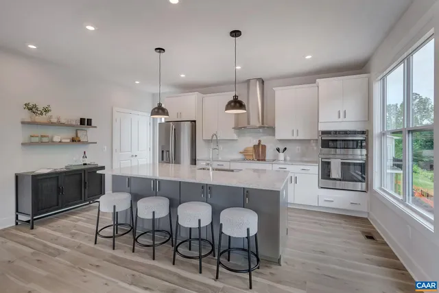 a large kitchen with cabinets wooden floor white stainless steel appliances and dining table