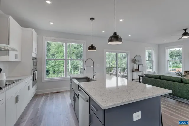 a kitchen with granite countertop a stove a sink a counter space and living room view