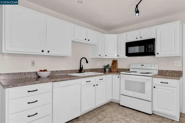 a kitchen with white cabinets and white appliances