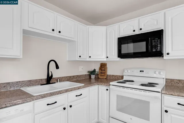 a kitchen with granite countertop white cabinets and white appliances