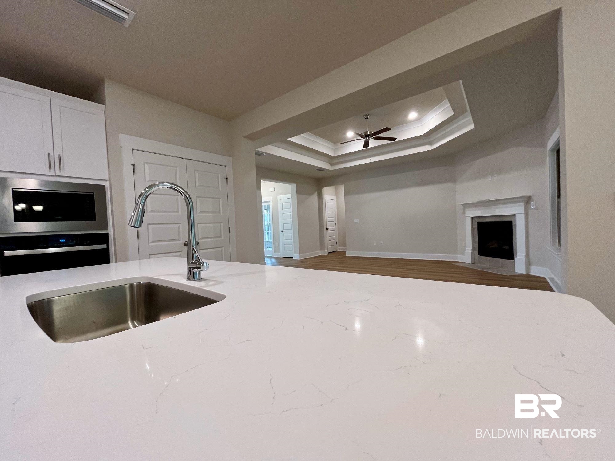 330 Barndling Street Fairhope, AL 36532 - Photo 15 of 31 Kitchen featuring hardwood / wood-style flooring, sink, light stone counters, ceiling fan, and a raised ceiling