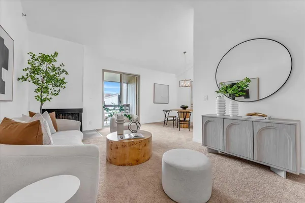 a living room with furniture a mirror and a potted plant